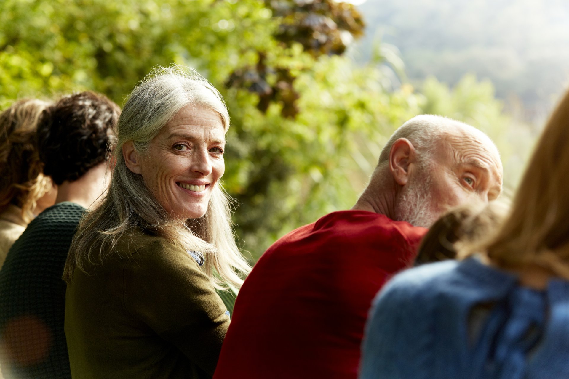 Woman sitting with a group outside similing at camera