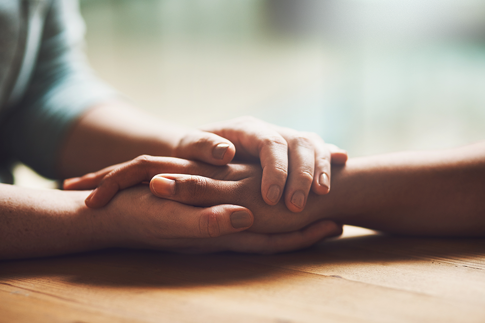 two people holding hands supportively 