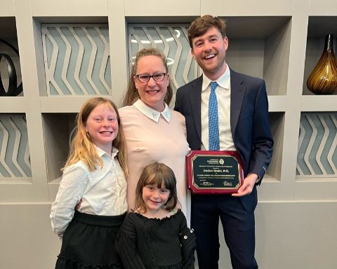 Group of two adults and two children. one adult is holding an award.