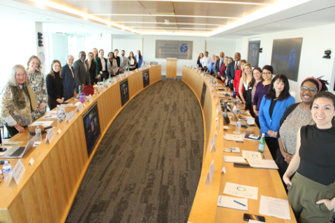 A large group of people posing for a photo in a boardroom meeting