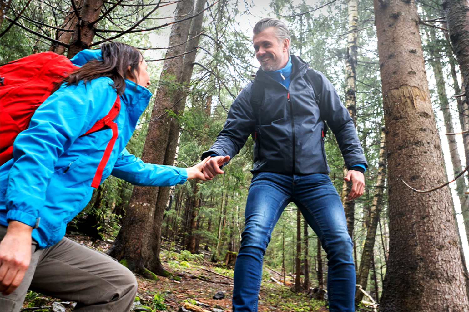 Man and woman smiling together on a hike in the woods